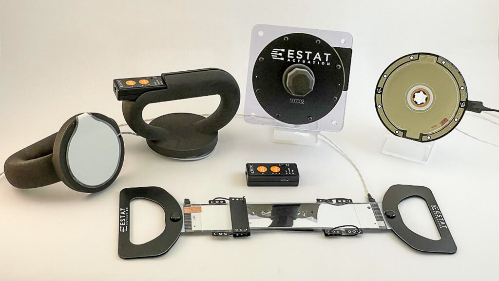 Image showing a collection of ESTAT's clutch hardware and electronic controls products. Products included in the picture include the Surface Clutch, Rotary Electroadhesive Clutch Stack (12 Nm) with Handle and Base, Rotary Electroadhesive Clutch Modular Unit (4 Nm), Battery-Powered Voltage Driver, and Linear Electroadhesive Clutch.